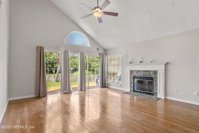 1430 Spindrift Cir E, Neptune Beach, FL 32266 - unfurnished living room featuring a ceiling fan, high vaulted ceiling, wood finished floors, a textured ceiling, and a stone fireplace