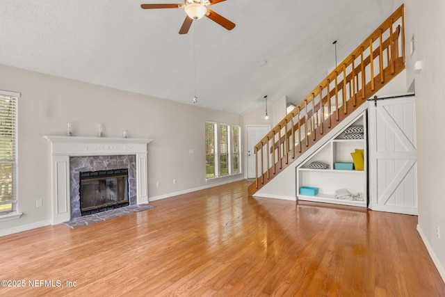1430 Spindrift Cir E, Neptune Beach, FL 32266 - unfurnished living room featuring ceiling fan, stairs, wood finished floors, a high end fireplace, and high vaulted ceiling