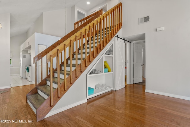 1430 Spindrift Cir E, Neptune Beach, FL 32266 - stairway with wood finished floors, high vaulted ceiling, a barn door, and recessed lighting