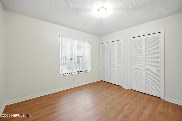 1918 Oak Cir, Atlantic Beach, FL 32233 - unfurnished bedroom featuring multiple closets, wood finished floors, and a textured ceiling