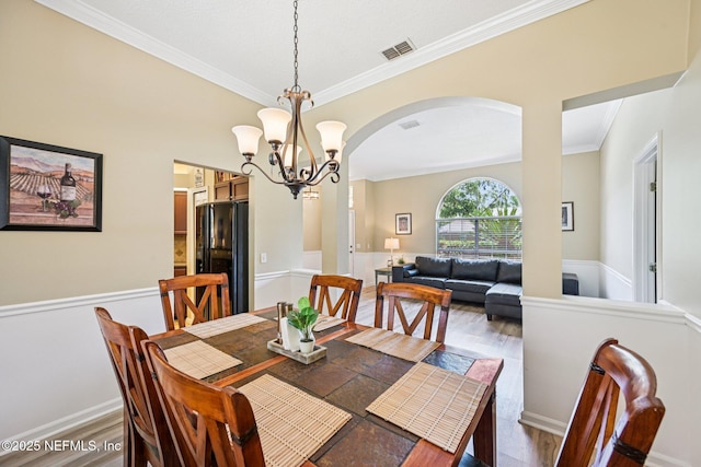 1400 Gibralter Ln, Fleming Island, FL 32003 - dining space with arched walkways, crown molding, a chandelier, and wood finished floors