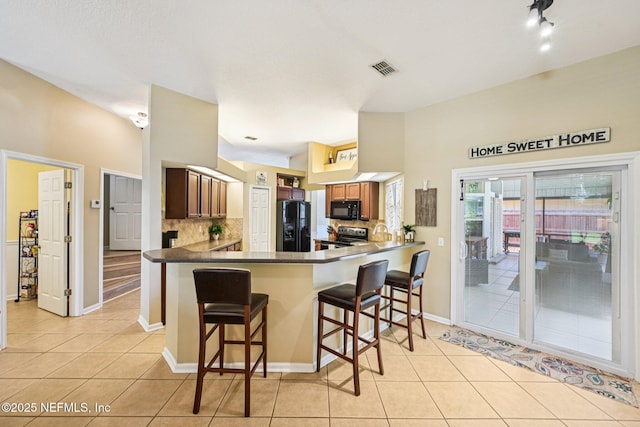 1400 Gibralter Ln, Fleming Island, FL 32003 - kitchen with light tile patterned floors, backsplash, black appliances, and a breakfast bar area