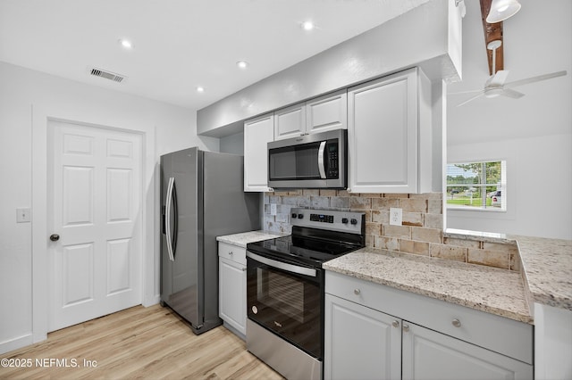 15 Katrina Pl, Palm Coast, FL 32164 - kitchen with stainless steel appliances, light wood-style flooring, decorative backsplash, white cabinets, and light stone counters