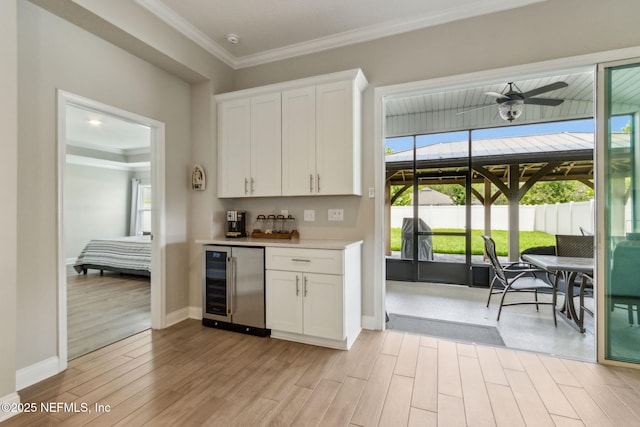 83316 Chapel Ct, Fernandina Beach, FL 32034 - kitchen with wine cooler, light wood finished floors, white cabinets, ornamental molding, and light countertops
