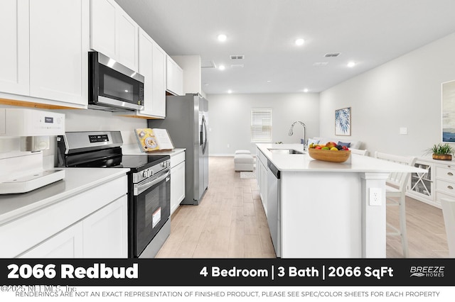 9018 Whinny Way Lot 276, Jacksonville, FL 32219 - kitchen with stainless steel appliances, light wood-style flooring, a kitchen island with sink, white cabinets, and light countertops