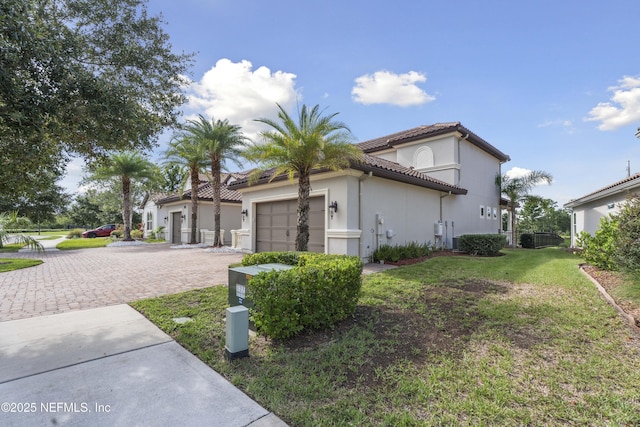 2936 Brettungar Dr, Jacksonville, FL 32246 - view of side of home with an attached garage, driveway, stucco siding, a tiled roof, and a yard