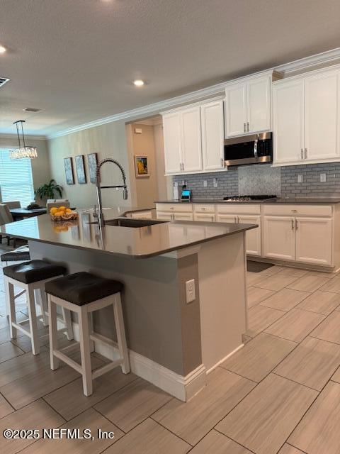 296 Latrobe Ave, Saint Augustine, FL 32095 - kitchen with appliances with stainless steel finishes, crown molding, white cabinetry, tasteful backsplash, and a center island with sink
