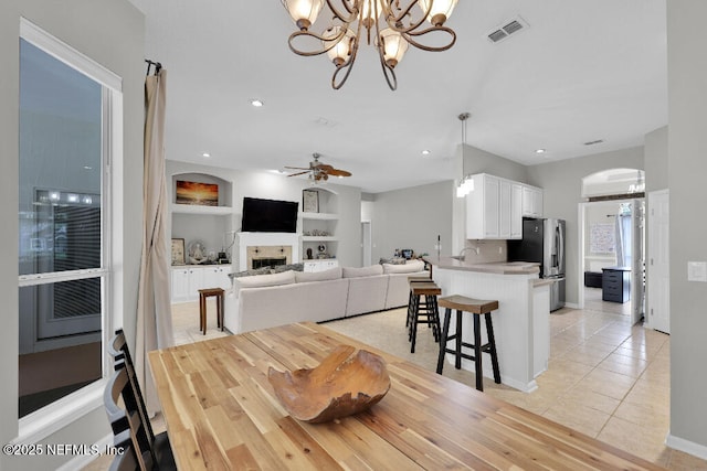 1728 Dartmoor Ln, Ponte Vedra, FL 32081 - dining space with a chandelier, light tile patterned floors, built in shelves, a fireplace, and arched walkways