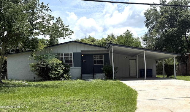 3421 Tarpon Dr, Jacksonville, FL 32277 - view of front of house featuring driveway, a carport, brick siding, a front yard, and board and batten siding