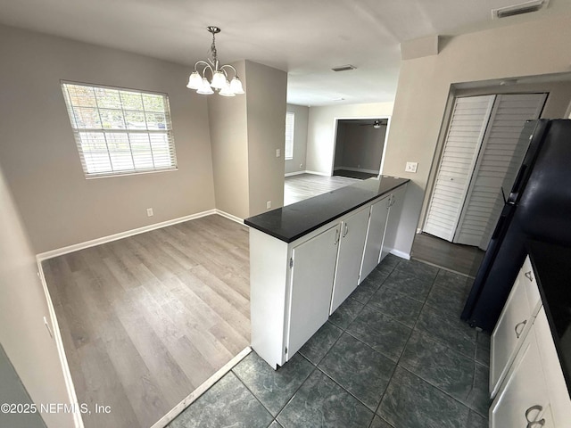 3421 Tarpon Dr, Jacksonville, FL 32277 - kitchen featuring a peninsula, dark countertops, a chandelier, pendant lighting, and white cabinetry