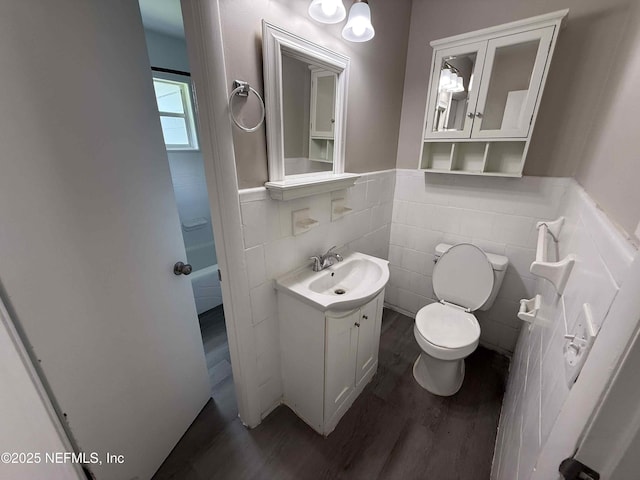 3421 Tarpon Dr, Jacksonville, FL 32277 - bathroom with wood finished floors, vanity, wainscoting, tile walls, and a bathtub