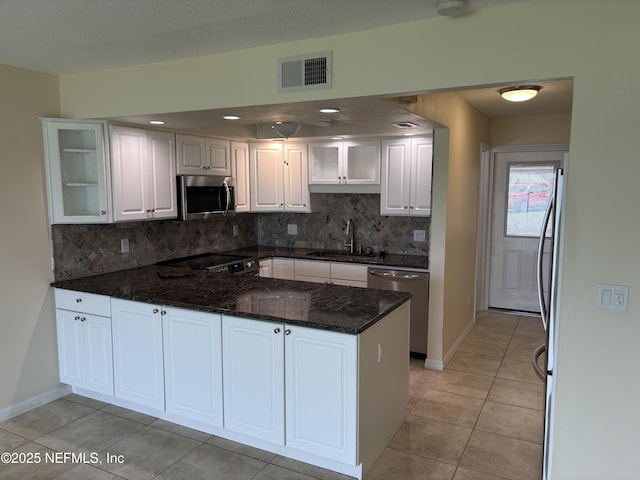 32 Ocean Palm Dr S Unit 320, Flagler Beach, FL 32136 - kitchen with appliances with stainless steel finishes, a peninsula, white cabinetry, tasteful backsplash, and glass insert cabinets