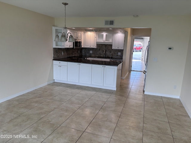 32 Ocean Palm Dr S Unit 320, Flagler Beach, FL 32136 - kitchen featuring stainless steel microwave, decorative backsplash, light tile patterned floors, and a peninsula
