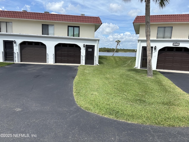 32 Ocean Palm Dr S Unit 320, Flagler Beach, FL 32136 - view of side of property with a tiled roof, asphalt driveway, a lawn, and an attached garage