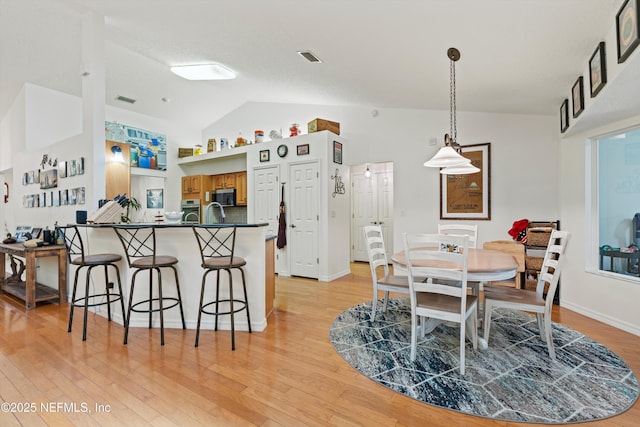 5566 Don Manuel Rd, Elkton, FL 32033 - kitchen with lofted ceiling, dark countertops, stainless steel microwave, brown cabinetry, and a kitchen breakfast bar