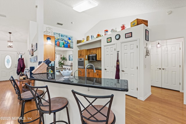 5566 Don Manuel Rd, Elkton, FL 32033 - kitchen with appliances with stainless steel finishes, a breakfast bar, dark countertops, brown cabinetry, and lofted ceiling