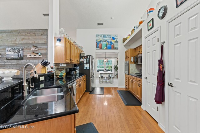 5566 Don Manuel Rd, Elkton, FL 32033 - kitchen featuring appliances with stainless steel finishes, tasteful backsplash, brown cabinets, and light wood finished floors