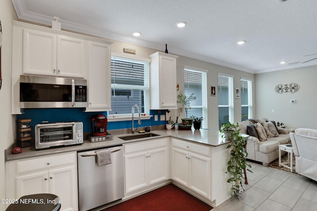 363 Latrobe Ave, Saint Augustine, FL 32095 - kitchen featuring stainless steel appliances, open floor plan, white cabinets, a peninsula, and ornamental molding