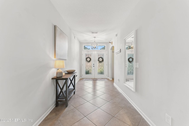 47 Mercutio Ln, Saint Augustine, FL 32092 - entryway with light tile patterned flooring, a textured ceiling, a chandelier, and french doors
