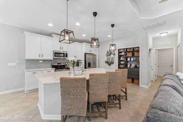47 Mercutio Ln, Saint Augustine, FL 32092 - kitchen with light tile patterned floors, decorative backsplash, white cabinetry, stainless steel appliances, and a kitchen island with sink