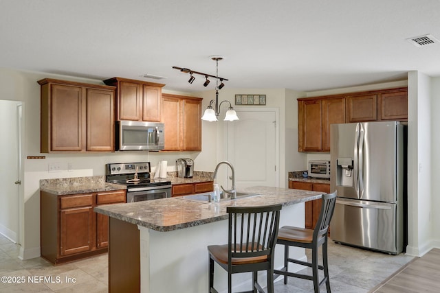 35 Root Ln, Saint Augustine, FL 32084 - kitchen with stainless steel appliances, brown cabinets, an island with sink, and pendant lighting