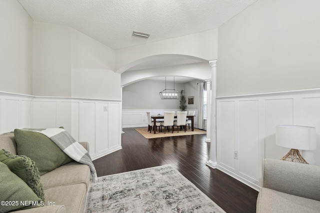 1083 Three Forks Ct, Saint Augustine, FL 32092 - living area with arched walkways, dark wood-style floors, a wainscoted wall, a decorative wall, and decorative columns