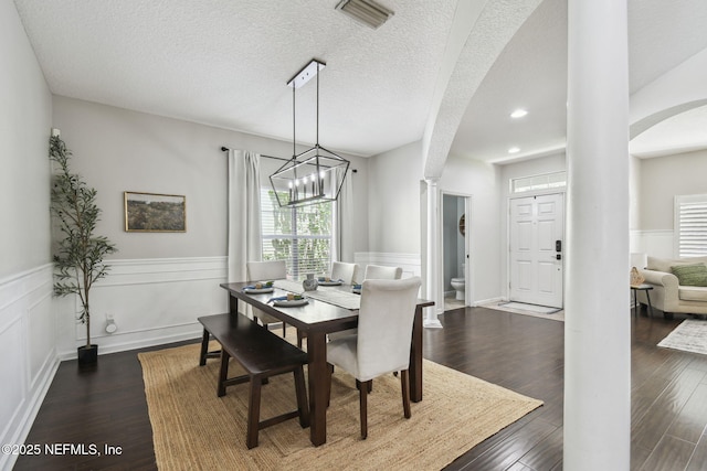 1083 Three Forks Ct, Saint Augustine, FL 32092 - dining space with arched walkways, wainscoting, decorative columns, a chandelier, and dark wood-style floors