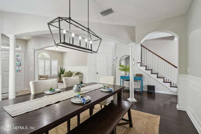 1083 Three Forks Ct, Saint Augustine, FL 32092 - dining room with decorative columns, wood finished floors, a wainscoted wall, a textured ceiling, and arched walkways
