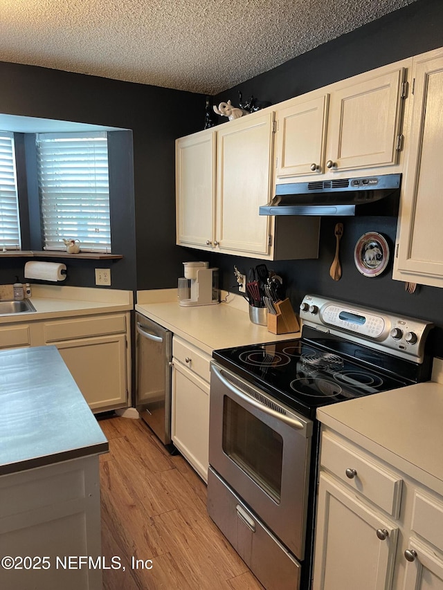 1855 N Alberta Ct, Middleburg, FL 32068 - kitchen with appliances with stainless steel finishes, under cabinet range hood, a textured ceiling, light countertops, and white cabinetry