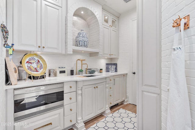 112 Harbourmaster Ct, Ponte Vedra Beach, FL 32082 - kitchen with stainless steel microwave, light wood-style floors, white cabinetry, and backsplash