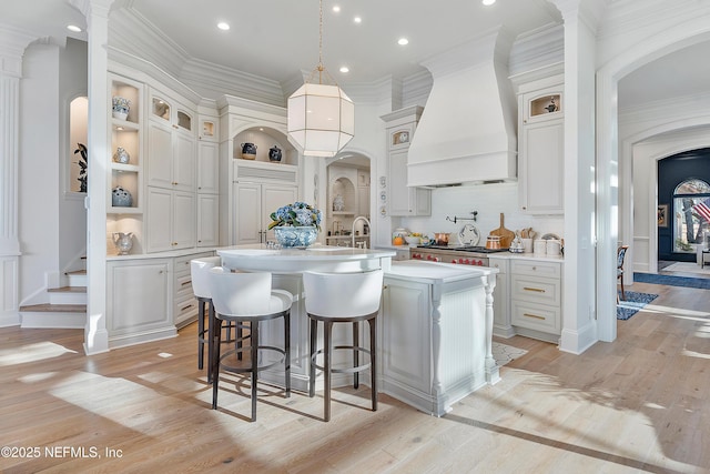 112 Harbourmaster Ct, Ponte Vedra Beach, FL 32082 - kitchen featuring custom range hood, an island with sink, light countertops, white cabinets, and light wood-style flooring