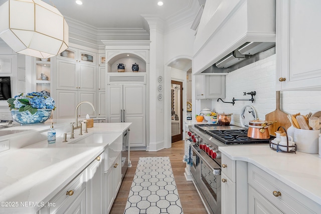 112 Harbourmaster Ct, Ponte Vedra Beach, FL 32082 - kitchen with premium range hood, double oven range, white cabinets, light countertops, and ornamental molding