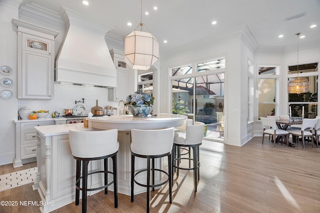 112 Harbourmaster Ct, Ponte Vedra Beach, FL 32082 - kitchen with a center island with sink, light countertops, tasteful backsplash, crown molding, and light wood finished floors
