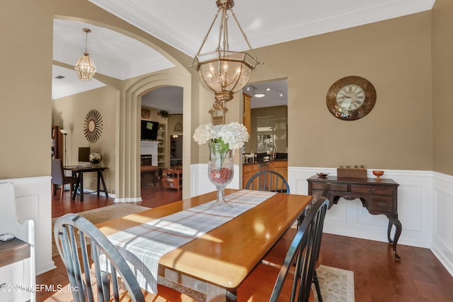 1685 Pinecrest Dr, Fleming Island, FL 32003 - dining area featuring arched walkways, wood finished floors, a wainscoted wall, ornamental molding, and a fireplace