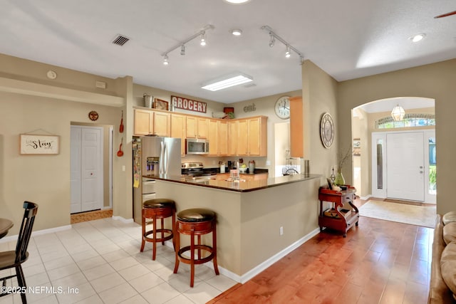 1685 Pinecrest Dr, Fleming Island, FL 32003 - kitchen featuring stainless steel appliances, light brown cabinets, a kitchen breakfast bar, arched walkways, and dark countertops
