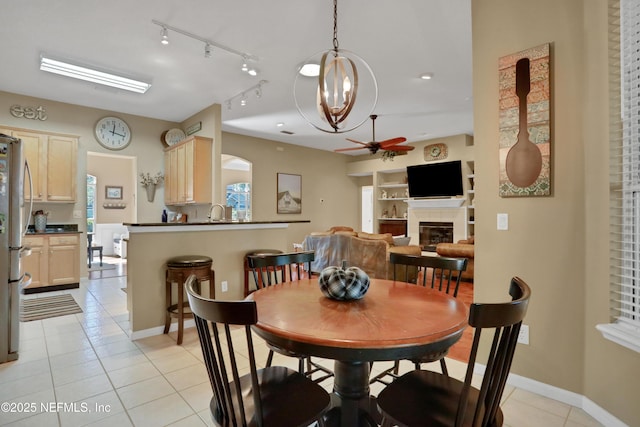 1685 Pinecrest Dr, Fleming Island, FL 32003 - dining space with a ceiling fan, light tile patterned flooring, a tile fireplace, track lighting, and plenty of natural light