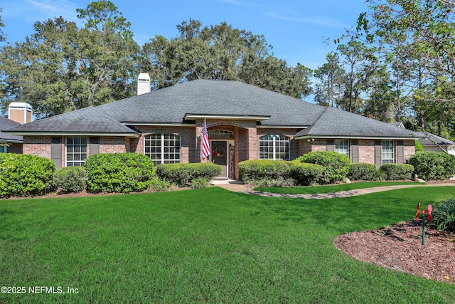 1685 Pinecrest Dr, Fleming Island, FL 32003 - ranch-style house featuring brick siding, a front lawn, a shingled roof, and a chimney