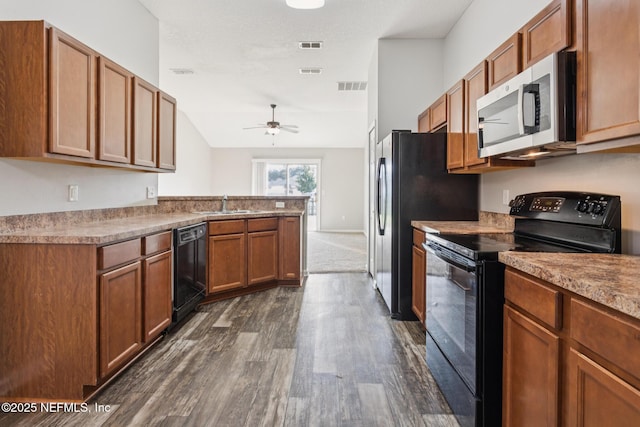 95886 Graylon Dr, Yulee, FL 32097 - kitchen with black appliances, dark wood-style floors, ceiling fan, brown cabinetry, and a peninsula