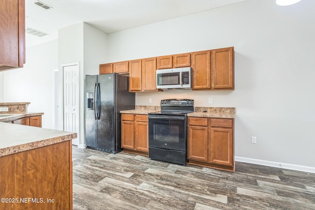 95886 Graylon Dr, Yulee, FL 32097 - kitchen with black appliances, wood finished floors, light countertops, and brown cabinets