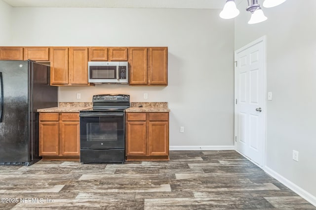 95886 Graylon Dr, Yulee, FL 32097 - kitchen with black appliances, dark wood-type flooring, brown cabinetry, and light countertops