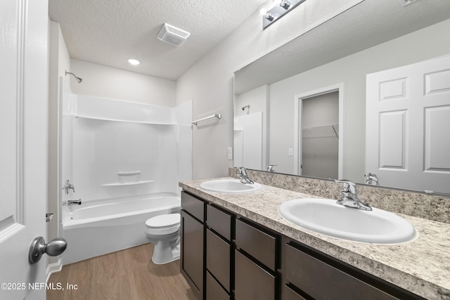 8077 Devoe St, Jacksonville, FL 32220 - full bath with wood finished floors, double vanity, tub / shower combination, and a textured ceiling