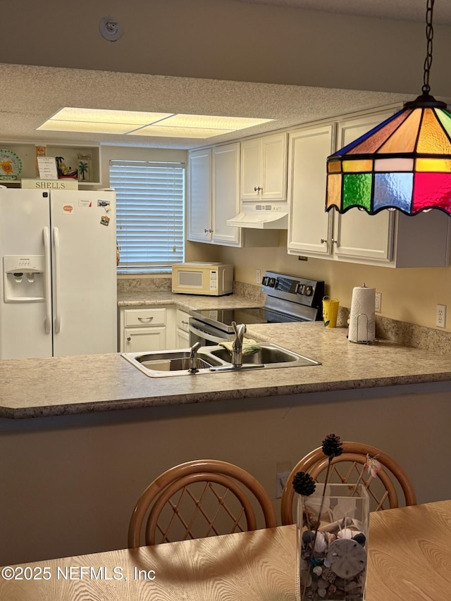 4250 A1A Unit R19, Saint Augustine, FL 32080 - kitchen with white appliances, under cabinet range hood, white cabinetry, light countertops, and a peninsula