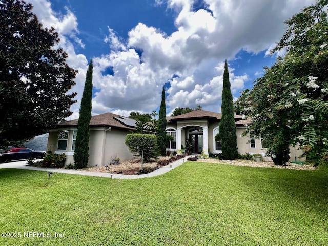16325 Magnolia Bluff Dr, Montverde, FL 34756 - view of front of house featuring stucco siding, a front lawn, and roof mounted solar panels