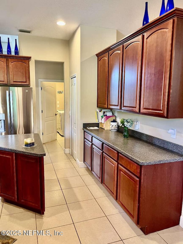 16325 Magnolia Bluff Dr, Montverde, FL 34756 - kitchen featuring stainless steel fridge with ice dispenser, light tile patterned flooring, dark brown cabinets, recessed lighting, and independent washer and dryer