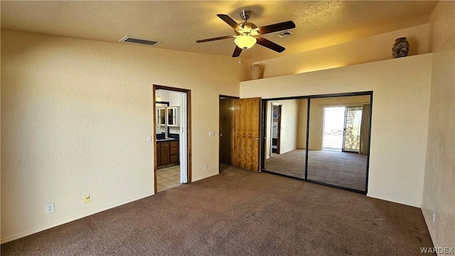 unfurnished bedroom featuring light carpet, a textured wall, visible vents, and a textured ceiling