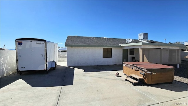 back of house featuring stucco siding, a hot tub, fence, and a patio