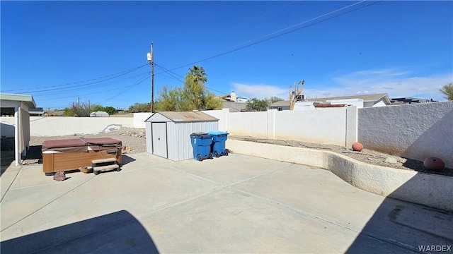 view of patio / terrace featuring a fenced backyard, an outdoor structure, a hot tub, and a shed