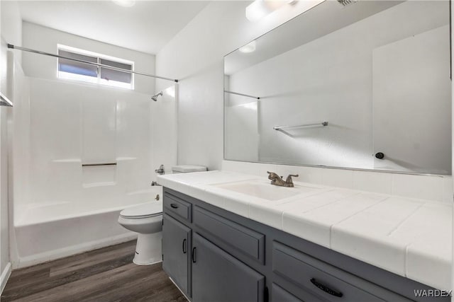 full bath with toilet,  shower combination, wood finished floors, and vanity