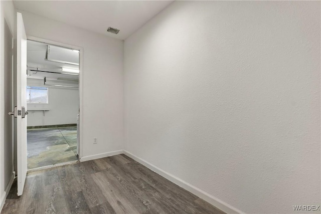 unfurnished room with dark wood-style floors, baseboards, and visible vents