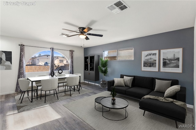 living room with visible vents, ceiling fan, baseboards, and wood finished floors